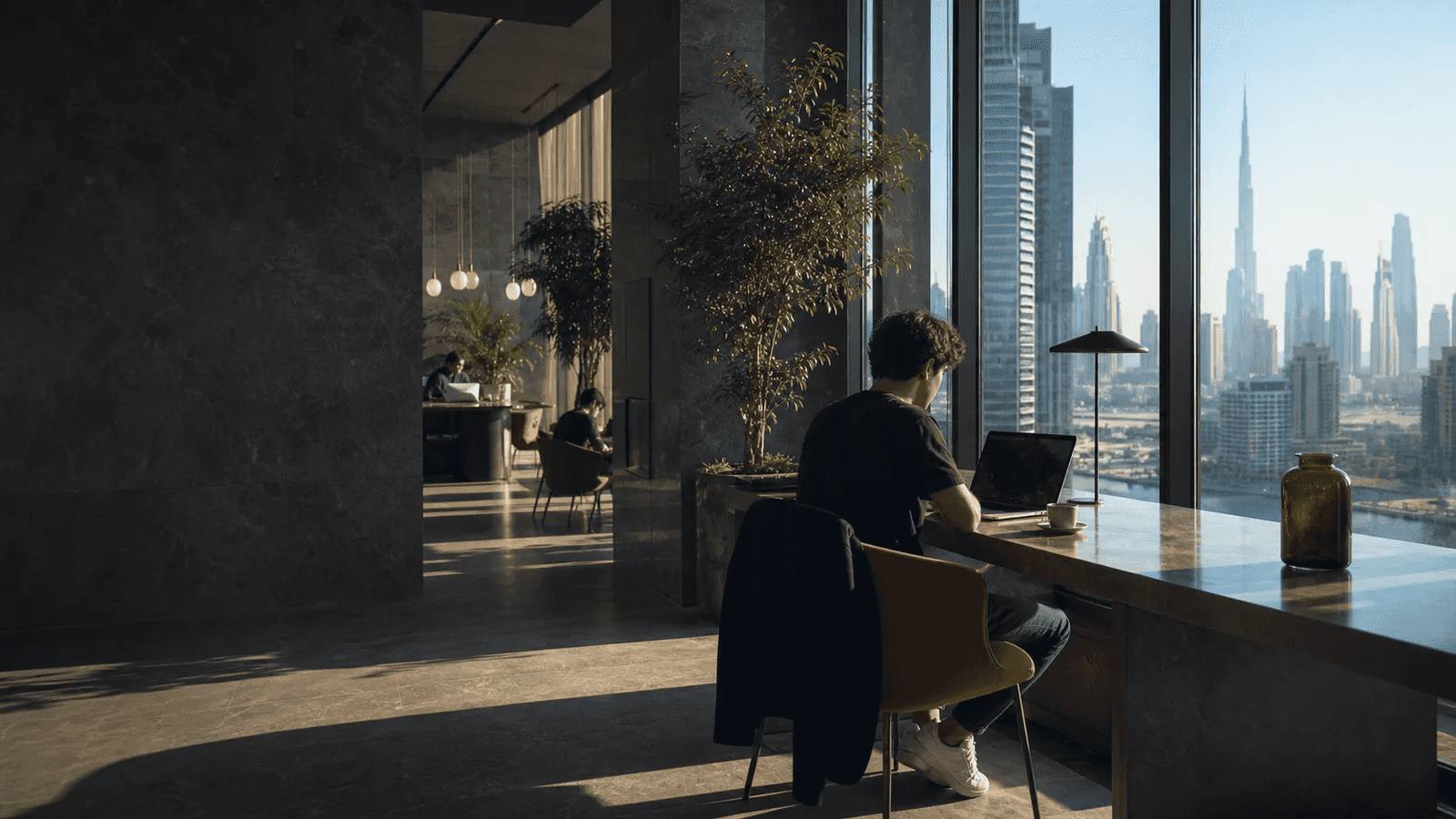 Remote worker at a coworking desk with the Dubai skyline beyond the windows