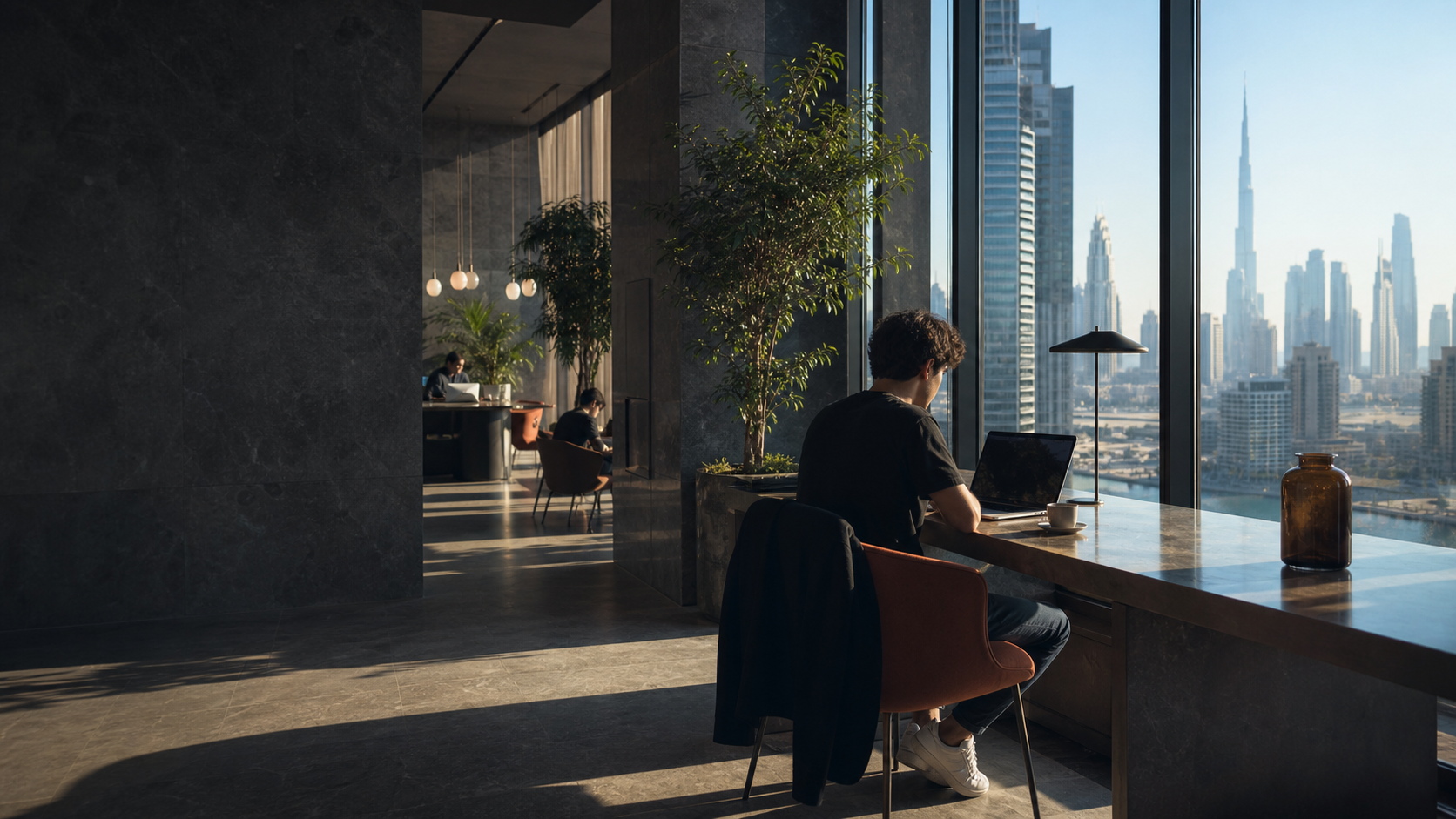 Remote worker at a coworking desk with the Dubai skyline beyond the windows